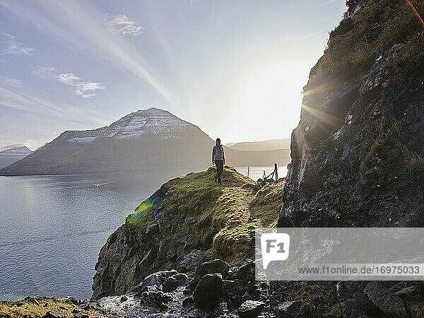 Woman hiking along oceanside trail in the Faroe Islands