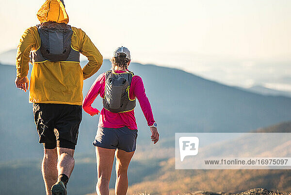 Man and woman trail running in mountains in morning
