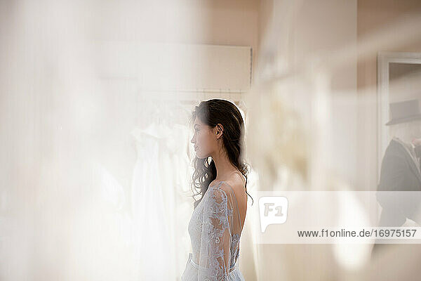 Junge Frau beim Anprobieren eines Kleides in einem Geschäft für Brautkleider