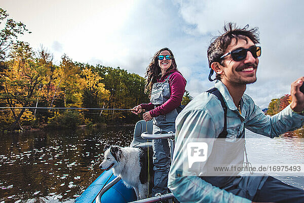 Mann und Frau Angler mit Hund lachend in einem Boot