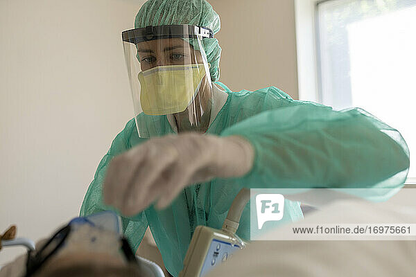 Krankenschwester kümmert sich um Patientin  geschützt vor Covid-19