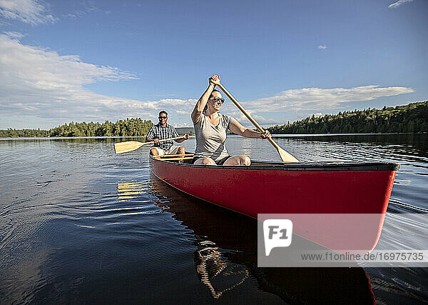 Lächelndes Paar paddelt mit dem Kanu über das ruhige Wasser des Bald Mountain Pond