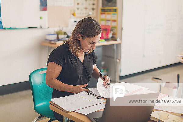 Elementary school teacher organizing papers in her classroom.