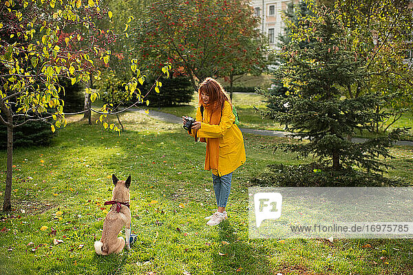 Junge Frau fotografiert Hund im Gras