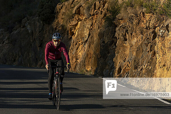 Ein Mann fährt mit dem Fahrrad auf der Bergstraße von Benissa nach Pinos.