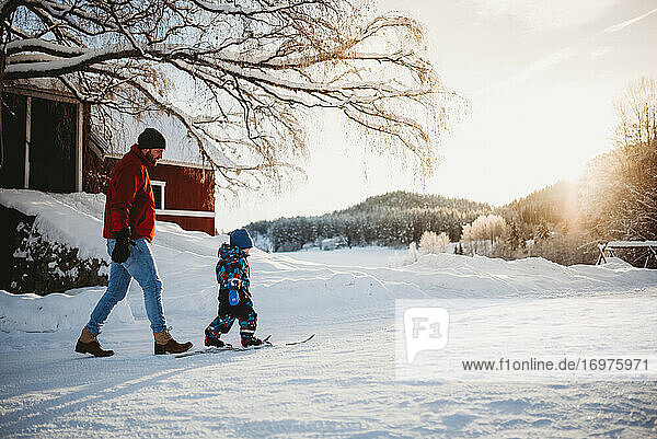 Father teaching son to cross country ski in winter in farm in Norway