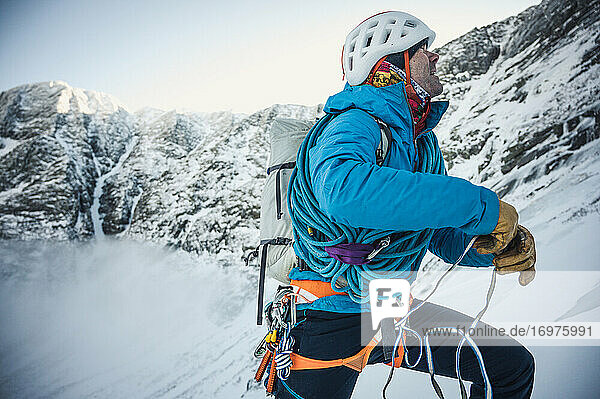 Ein männlicher Bergsteiger bindet sich während einer alpinen Klettertour in Maine an seinem Anker fest