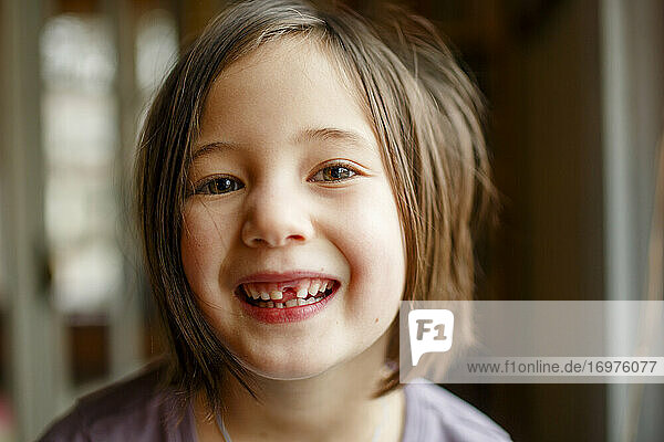 Nahaufnahme eines stolzen kleinen Mädchens  das mit einem breiten Lächeln seinen fehlenden Zahn zeigt