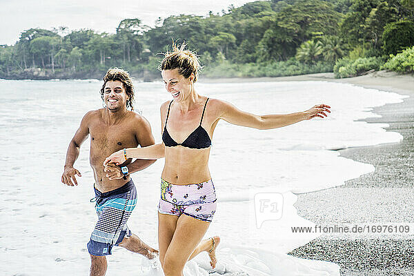 Multi ethnic couple on costa rican vacation running on beach