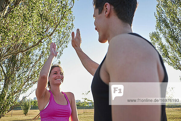 Athleten  die sich beim Training in einem öffentlichen Park die Hände reichen