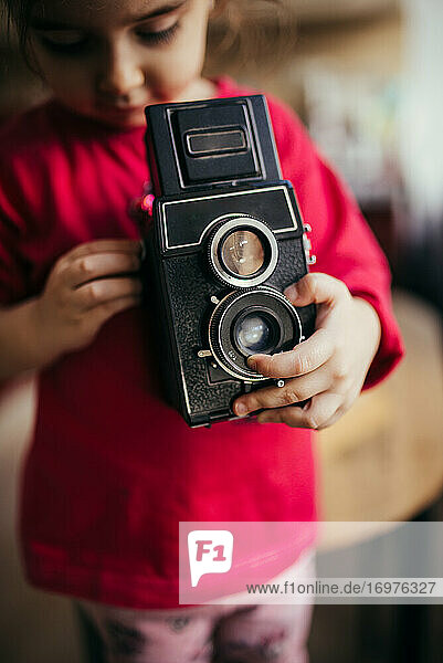Kleines Mädchen beim Einstellen einer alten analogen Kamera.
