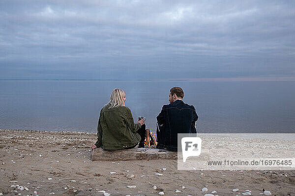 Junges Paar mit Tee am Seeufer