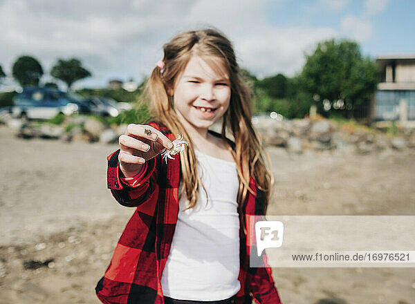 Young girl holding small dead crab on the beach