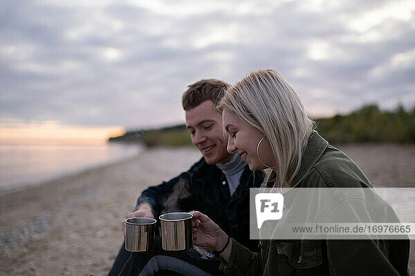 Fröhliches Paar stößt mit Tassen Tee an