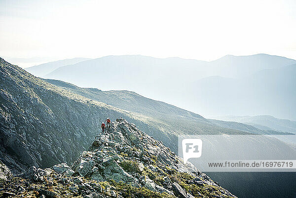 Man and woman walking on ridge during morning in mountains