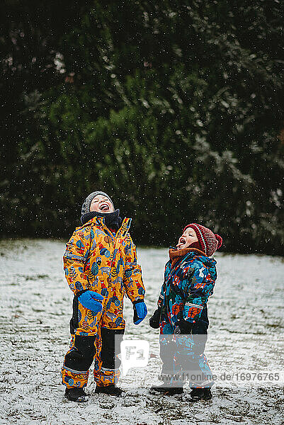 Lustige Kinder strecken an einem kalten  verschneiten Tag die Zunge heraus  um Schneeflocken zu kosten