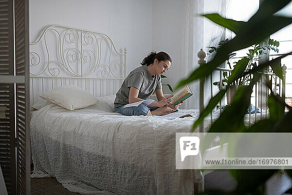 Junge Frau liest ein Buch während der Prüfungsvorbereitung zu Hause