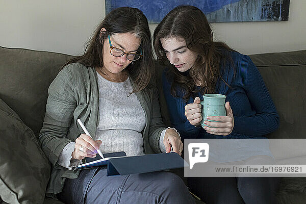 A mother and daughter work on a tablet together