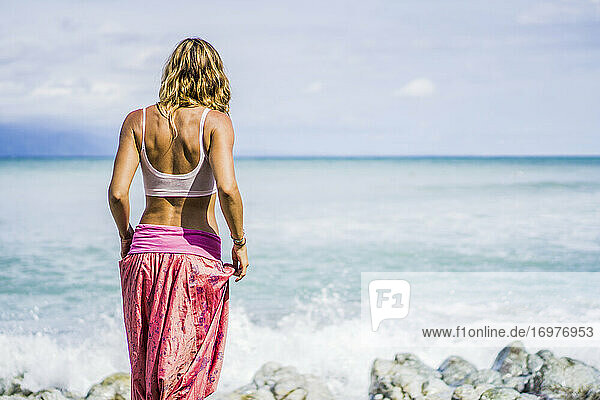 Schöne Frau in Yogahose schaut auf das Meer hinaus