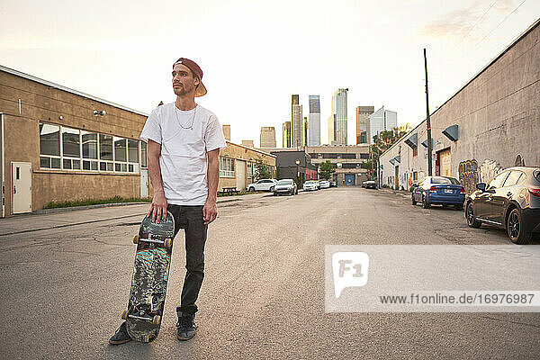 Junger Skateboarder auf der Straße im städtischen Industriegebiet d