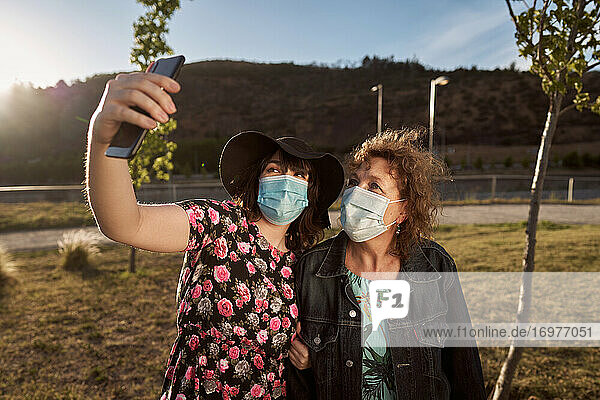 Eine Latina-Mutter und ihre Tochter machen ein Selfie-Foto mit einem Mobiltelefon und