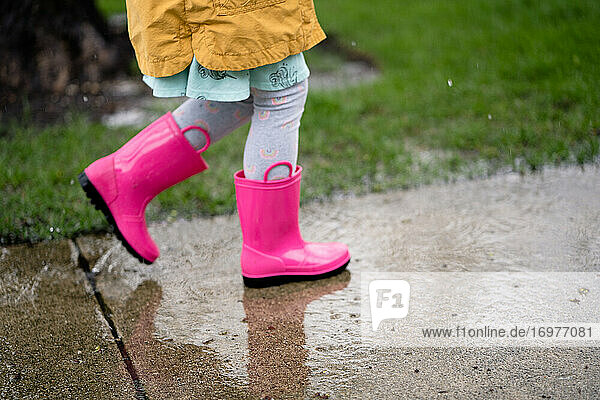 Seitenansicht der unteren Hälfte eines Mädchens  das im Regen spazieren geht  in Regenbögen
