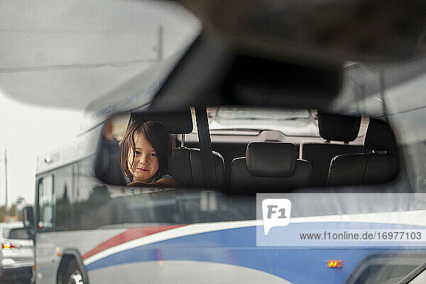 ein süßes kleines Mädchen wird im Rückspiegel eines Autos reflektiert