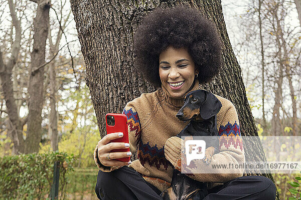 ein kubanisches Mädchen macht ein Selfie mit ihrem Dackel im Park