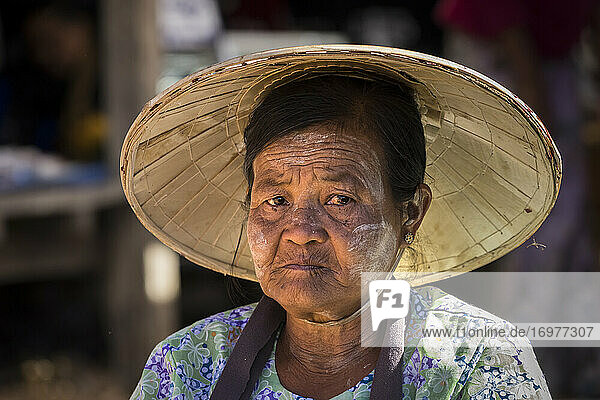 Porträt einer erwachsenen Frau mit kegelförmigem Hut auf einem Straßenmarkt im Dorf