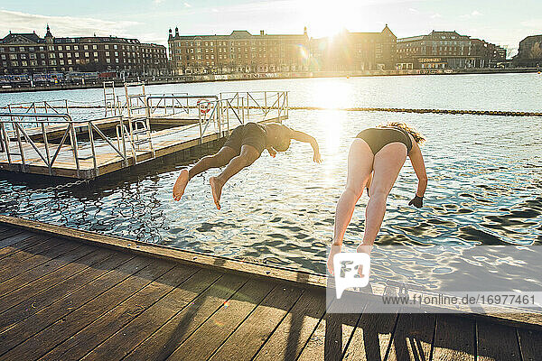 Zwei Freunde unterschiedlichen Alters und unterschiedlicher Rasse springen in Dänemark ins kalte Wasser