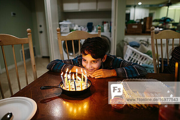 Junge lächelt die Kerzen auf seiner gusseisernen Geburtstagstorte an