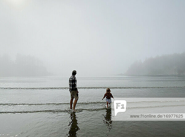A father and daughter play in the shallow water off the coast of OR.