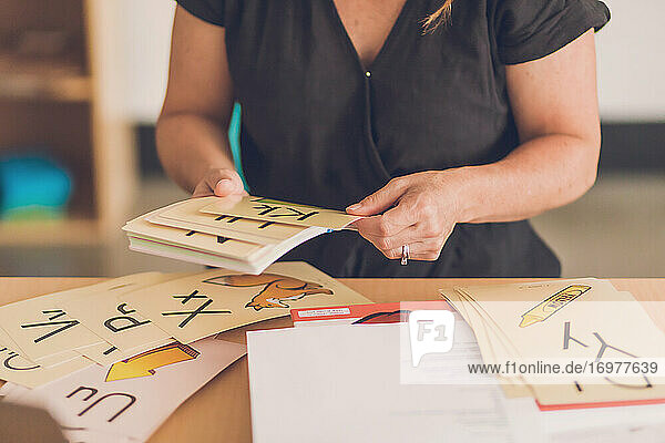 Female teacher sorting out alphabet picture cards in her classroom.