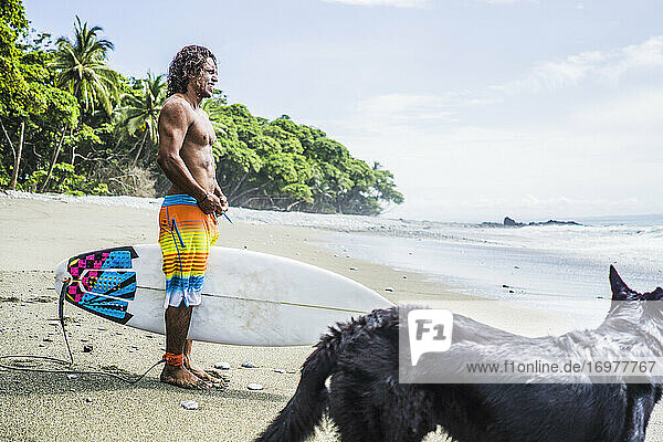Surfer mit Hund bei der Vorbereitung eines Surftrips am Strand