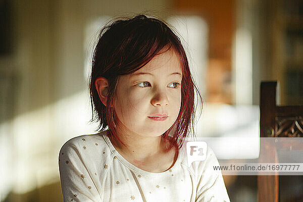 Portrait of small child with dyed red hair sitting in beautiful light