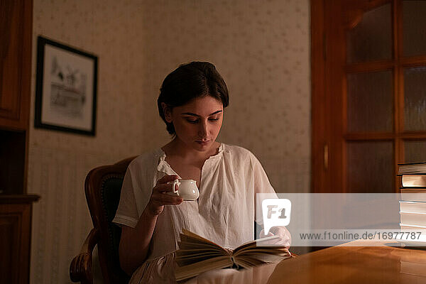 Junge Frau mit Tasse  die ein Buch liest