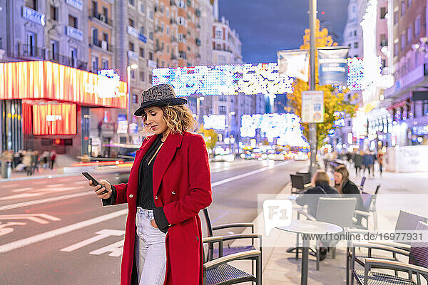 Frau in roter Jacke benutzt ihr Smartphone in der Stadt