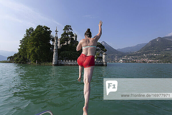 Ein Mädchen springt vom Bug eines Bootes in einen See in Italien