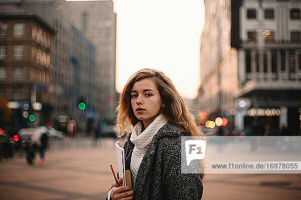Portrait of teenage student girl standing in city during autumn
