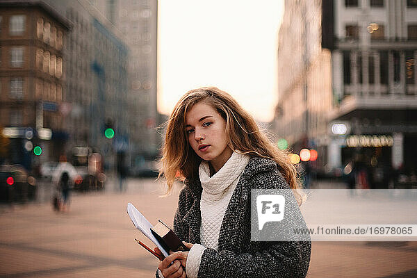 Portrait of cute teenage student girl standing in city