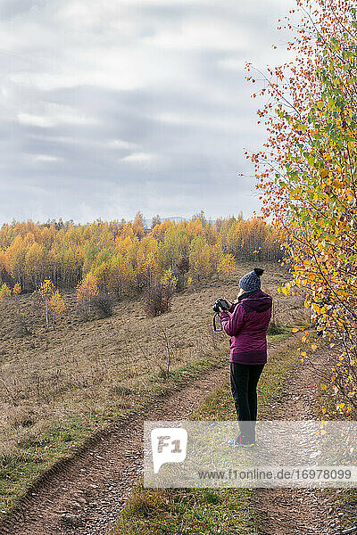 Frau fotografiert Bäume mit gelben Blättern  Herbst auf dem Hügel