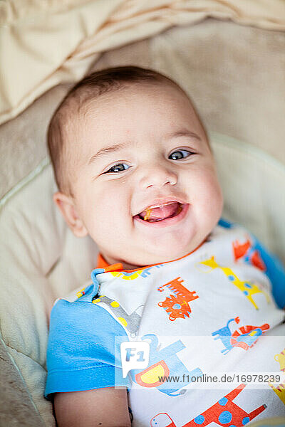 Lächelndes Baby isst seine erste feste Mahlzeit
