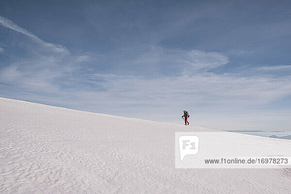 Junger Mann wandert bergauf auf Eis Schnee gegen blauen Himmel  Gredos  Spanien