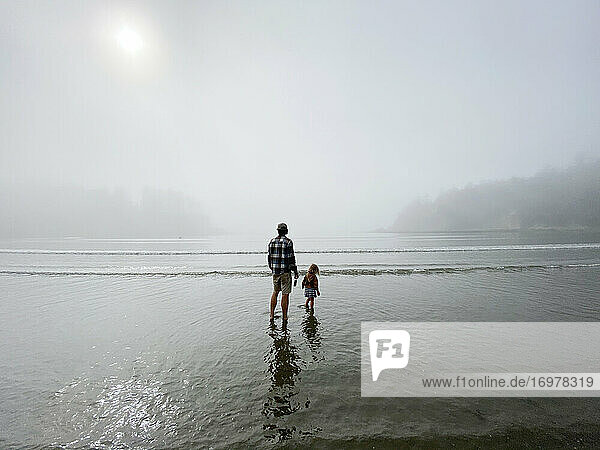 A father and daughter play in the shallow water off the coast of OR.