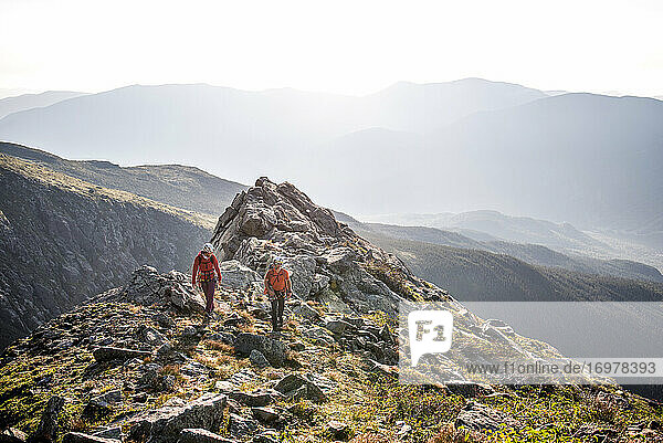 Man and woman walking on ridge during morning in mountains