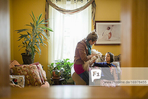 Gerahmte Ansicht von Frau und Kind  die gemeinsam eine Katze im Wohnzimmer streicheln