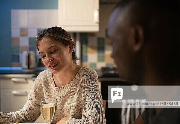 Lächelnde Frau im Gespräch mit schwarzem Freund beim Abendessen
