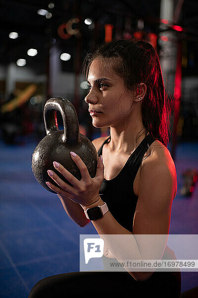 Starke Frau beim Training mit der Kettlebell in einem modernen Fitnessstudio