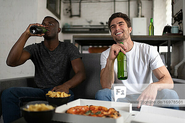 Fröhliche multikulturelle Freunde trinken Bier und sehen sich ein Fußballspiel an