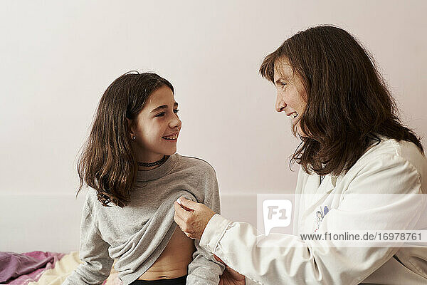 Weiblicher Arzt  der einem Mädchen in ihrem Bett die Temperatur auf einem Thermometer zeigt. Hausarzt Konzept